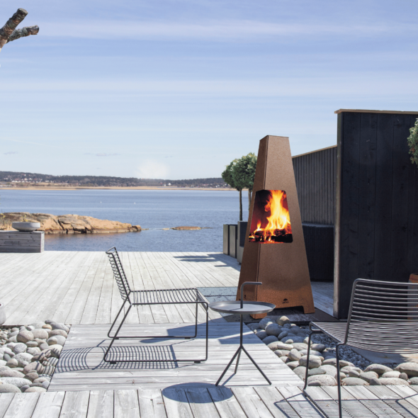 Stor utendørs peis i cortenstål på en terrasse ved sjøen