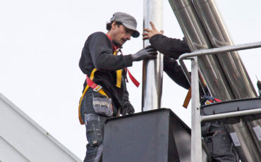 To menn som gjør piperehabilitering med stålpipe på taket